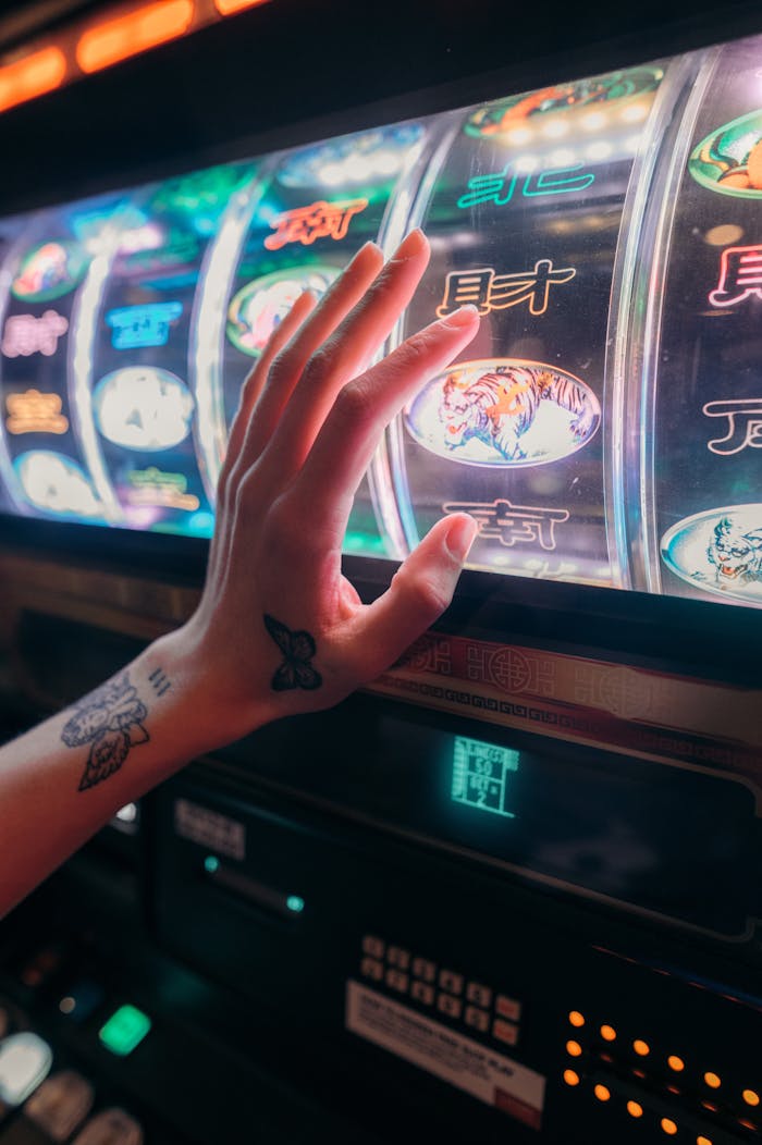 Tattooed hand playing slot machine in vibrant casino setting, emphasizing chance and excitement.